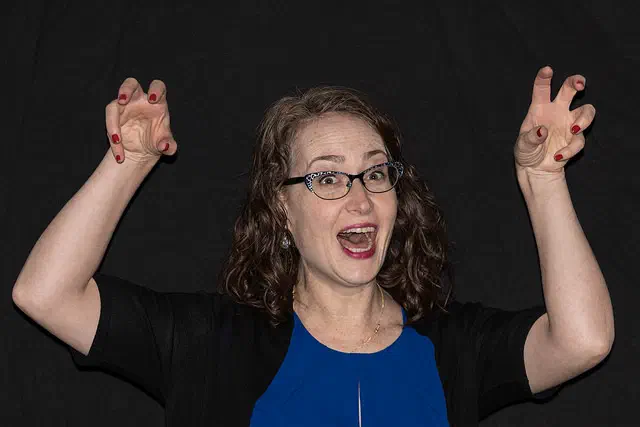 Amy Lewis smiling with both arms raised during a headshot session
